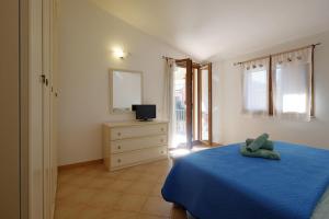 um quarto com uma cama azul e uma cómoda com um espelho em Il giardino di Marina em Teulada
