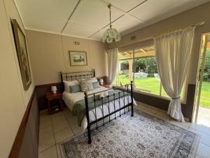 a bedroom with a bed and a large window at Warbler's Haven in Wakkerstroom