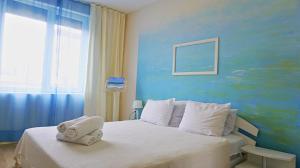 a bedroom with a white bed with a blue wall at Апартамент Деа - Apartment Dea in Byala