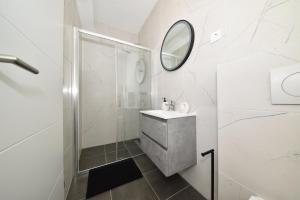 a white bathroom with a sink and a mirror at SOFIA'S Studio & Room in Zadar