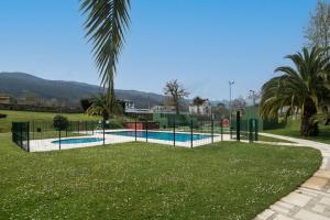 a swimming pool in a park with a palm tree at Apartamento Tejasturias in Noriega