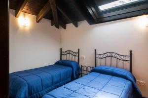two beds in a room with blue sheets at Apartamento Tejasturias in Noriega