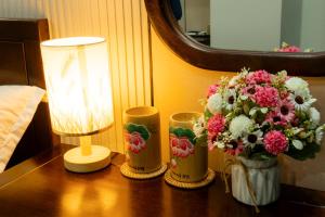 einen Tisch mit einer Lampe und einer Vase Blumen darauf in der Unterkunft Lotus 68 Hotel in Ninh Bình