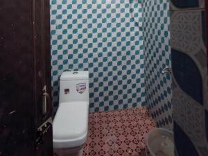 uma casa de banho com um WC com azulejos azuis e brancos em Shree Mahakaal Inn by StayApart em Gupta Kāshi