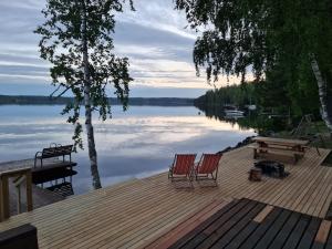 a dock with two chairs and a picnic table on a lake at Cozy 4BR Lakeside Cottage with Sauna & Outdoor Grill in Lahti