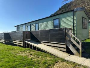 a green house with a wooden ramp in front of it at Swift Bordeaux Sea View 10 in Ardentinny