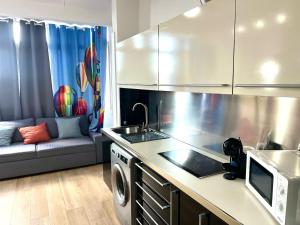 a kitchen with a microwave and a couch in a room at Apartamento Velázquez Aeropuerto C in Málaga
