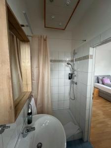 a white bathroom with a shower and a sink at Villa Theresia in Benediktbeuern