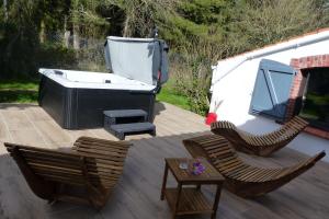 a patio with a tub and two chairs and a table at Nature et partage - Jacuzzi - Wifi in Grand-Landes