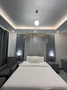 a bedroom with a large white bed and a chair at Vorano Boutique Hotel Islamabad in Islamabad