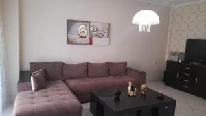a living room with a brown couch and a table at holidays Nea Peramo in Nea Peramos