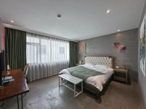 a bedroom with a bed and a desk and a window at Suzhou Unique Space Design Art Hotel in Suzhou