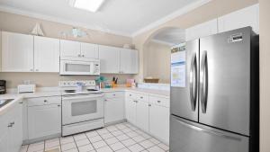 a kitchen with white cabinets and a stainless steel refrigerator at 422 Cypress Bend Condo in North Myrtle Beach