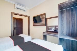 una camera d'albergo con due letti e una tv di Collection O Pusat Kota Pekanbaru Near Rumah Sakit Prima Formerly King's Homestay a Pekanbaru