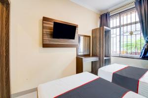 una camera d'albergo con due letti e una TV a schermo piatto di Collection O Pusat Kota Pekanbaru Near Rumah Sakit Prima Formerly King's Homestay a Pekanbaru