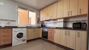 a large kitchen with a washer and dryer in it at Casa Frijol 20metres from the beach in Los Alcázares