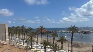 a beach with palm trees and a harbor with boats at Casa Frijol 20metres from the beach in Los Alcázares