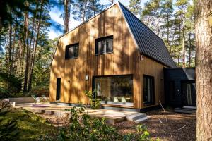 een huis in het bos met een zwart dak bij Waldvilla Haus Gustav am Ostseestrand in Lubmin