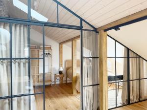 リエパーヤにあるKurshu Mansards - Modern Loftのガラスの壁とウッドフロアの客室です。