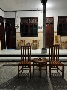 Ngurah Rai International AirportD nux House的建筑物前的两把椅子和一张桌子