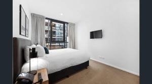 ein weißes Schlafzimmer mit einem Bett und einem Fenster in der Unterkunft CBD Resort with King Suite, Pool, Gym, Sauna, Cafe, Wifi, IGA in Adelaide