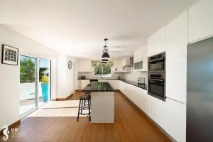 a white kitchen with a counter and a table at 180 degree Ocean Views, Pure Paradise in Luz