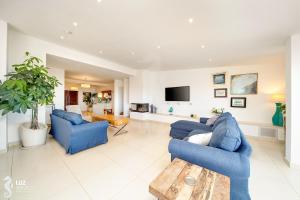 a living room with two blue couches and a tv at 180 degree Ocean Views, Pure Paradise in Luz