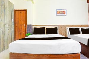 a bedroom with two beds and a wooden door at Hotel O Rama Utsav in Gwalior