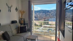 a living room with a couch and a view of a balcony at La parenthèse du lac in Gérardmer