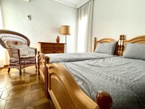 a bedroom with two beds and a chair at Home Campoamor in Orihuela Costa +25 photos