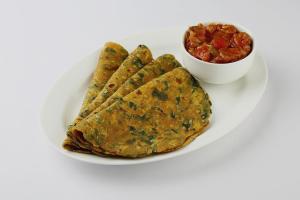 a white plate with a plate of food and a bowl of salsa at Hotel O Rama Utsav in Gwalior