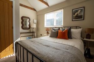 une chambre avec un lit avec des oreillers et un miroir dans l'établissement Dunes Cottage, à Lowestoft