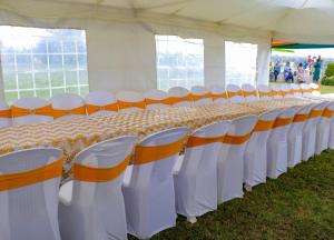 a long table with orange and white chairs in a tent at Enkapune Resort Naivasha in Naivasha