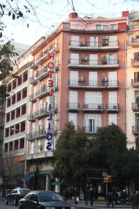 un grand bâtiment rose avec un panneau d'hôtel dans l'établissement Ilios, à Thessalonique
