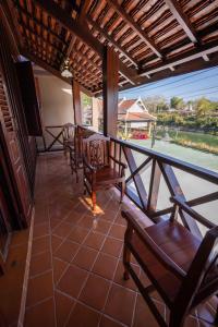 a balcony with chairs and a table and a view of a pool at Villa Deux Rivières Hotel in Luang Prabang