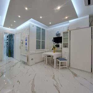 a white kitchen with a marble floor and a table at Sharon Apartment in Victoria Beach in Menton