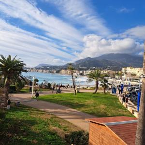 a park with palm trees and people walking on a sidewalk at Sharon Apartment in Victoria Beach in Menton +33 photos