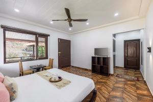 une chambre avec un lit et un ventilateur de plafond dans l'établissement Alaya Stays Madhuram Villa - Pet-Friendly 5 BHK Hillside Retreat With Garden & Balcony, à Dhanaulti