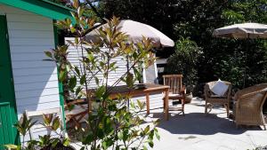 una mesa, sillas y una sombrilla en el patio en Ferienwohnung am Kniebach, en Immenstaad am Bodensee