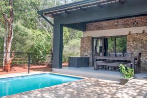 a patio with a pool and a table and a bench at Die Watergat in Marloth Park