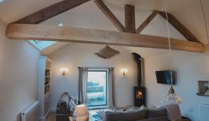 a living room with a ceiling with wooden beams at Stock Barn in Youlgreave