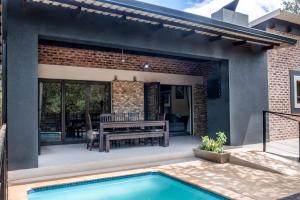 a patio with a pool and a table and a bench at Die Watergat in Marloth Park