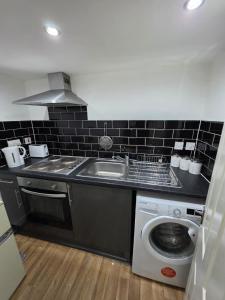 a kitchen with a sink and a washing machine at Cozy Studio Flat, 7mins from CENTRE, Parking, WiFi & Netflix in Killingbeck