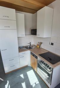 a kitchen with white cabinets and a sink and a stove at Ferienwohnung am Backhaus 2 in Weimar +6 photos