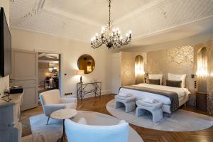 a bedroom with a bed and chairs and a chandelier at Guesthouse Domaine du Chalet in Chigny-les-Roses