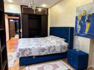 ein Schlafzimmer mit einem blauen Bett und einem Gemälde an der Wand in der Unterkunft Appartement à Dar bouaaza in Tamaris + 9 Fotos