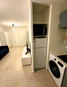 a kitchen with a refrigerator and a washing machine at Cozy studio avec balcon aux portes de Genève in Ambilly