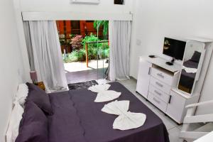 a bedroom with a purple bed with pillows on it at Hotel Vista Bella in Ilhabela