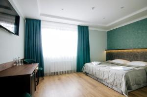 Un dormitorio con una cama y un escritorio y una ventana. en Soprano Inn Hotel, en Pasiky-Zubryts'ki