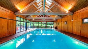 a large swimming pool in a building with wooden walls at Guesthouse Domaine du Chalet in Chigny-les-Roses
